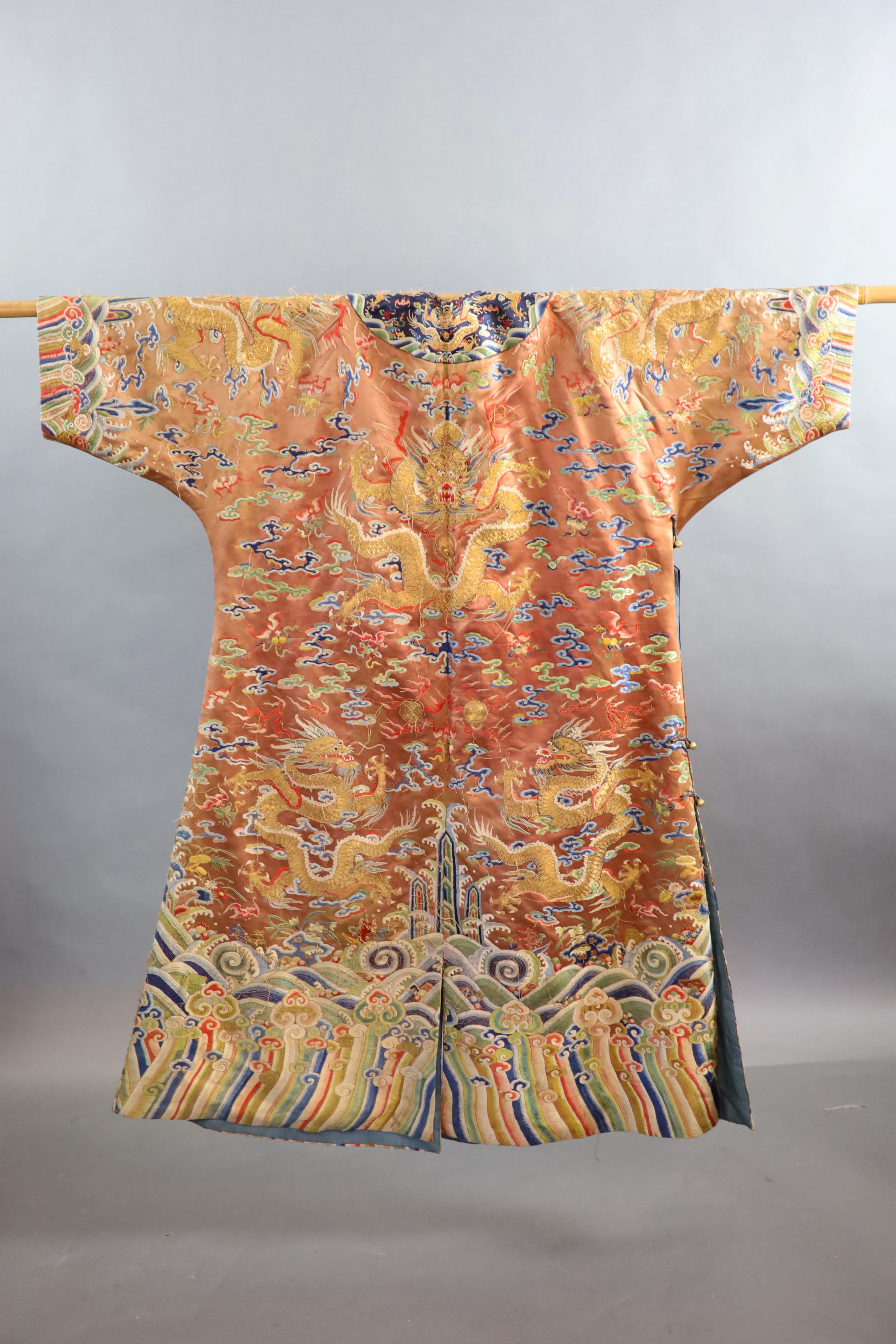 A Chinese apricot embroidered silk ‘dragon’ formal court robe, jifu, late Qing Dynasty, 131cm long, some alterations